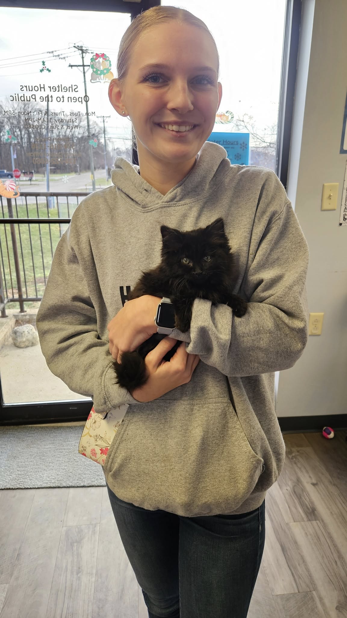 A staff member holding a fluffy black kitten inside the shelter lobby